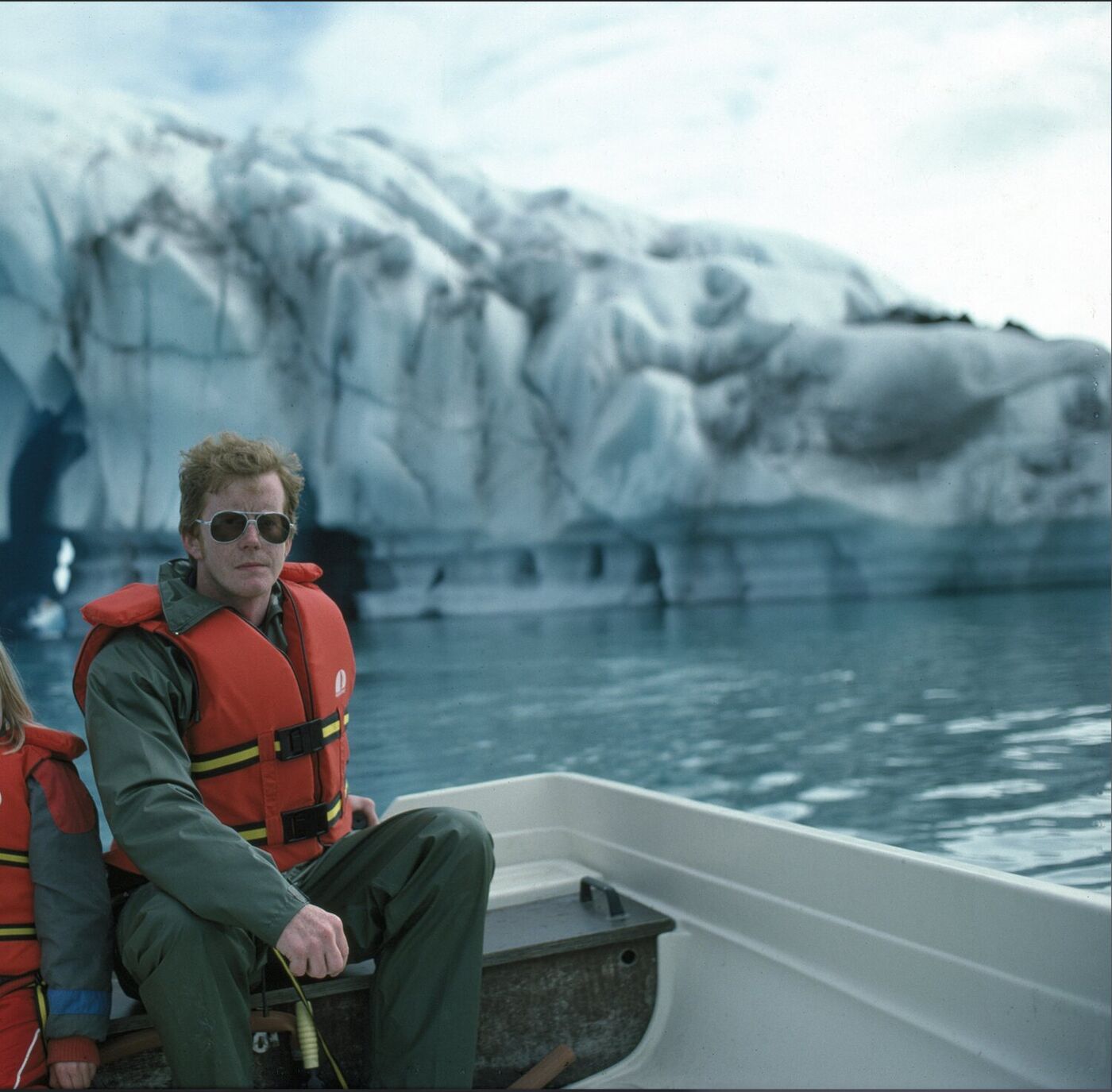 Guðbrandur in a small boat on Jökulsárlón in 1985, a wall of glacier ice behind him