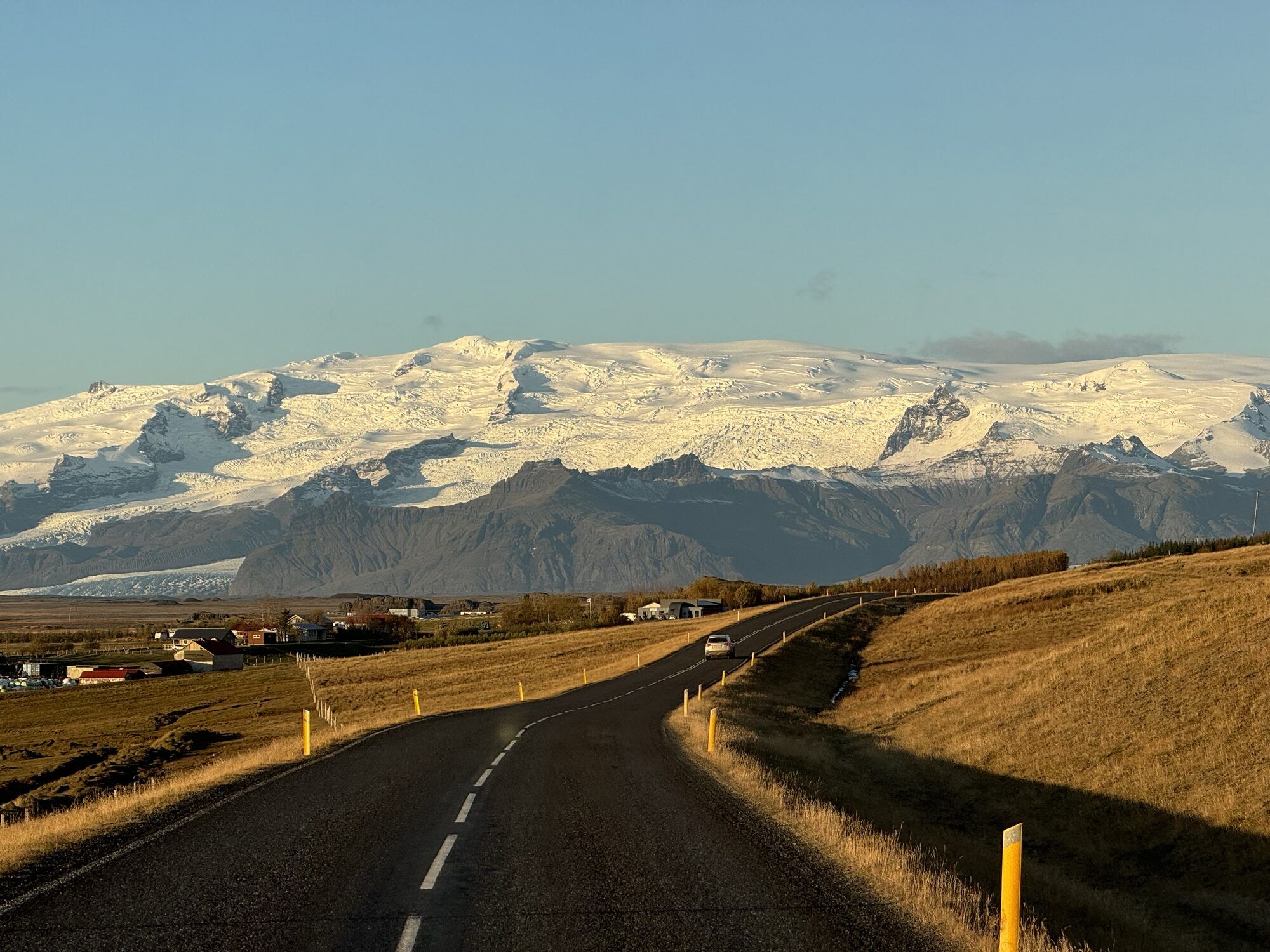The coast road curving towards the snow-covered Vatnajökull ice cap in low evening light