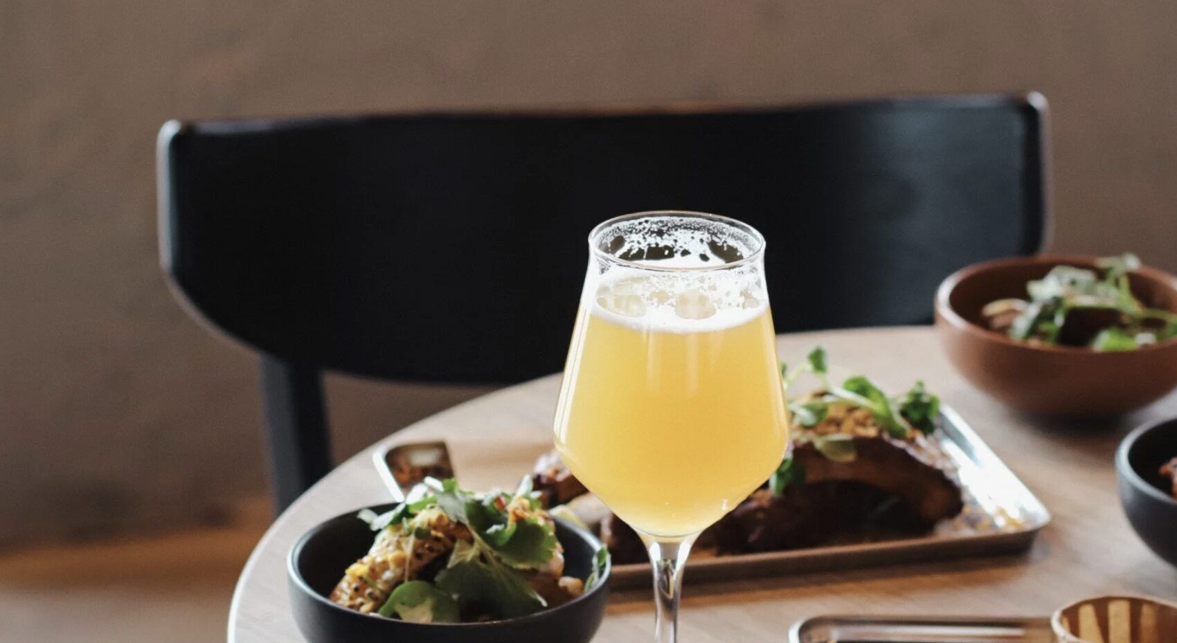 A glass of local beer beside plates of food at a restaurant table