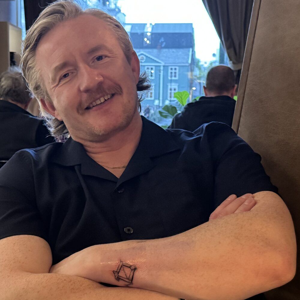 Páll Guðbrandsson, arms crossed, smiling in a café